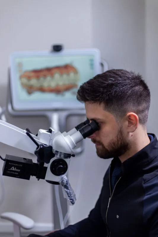 Dr. Marcos Vinícius trabalhando ao microscópio odontológico